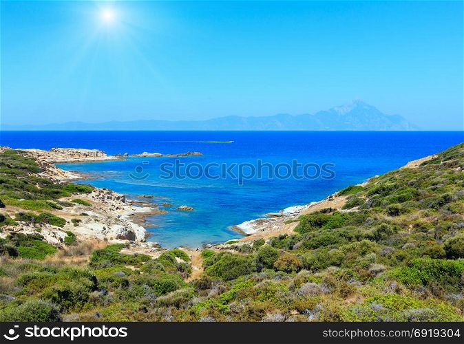 Summer sunshiny stony sea coast landscape with Athos mount view in far (Halkidiki, Sithonia, Greece).
