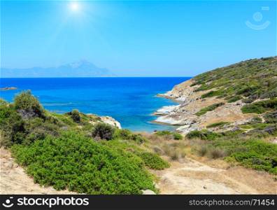 Summer sunshiny stony sea coast landscape with Atthos mount view in far(Halkidiki, Sithonia, Greece).