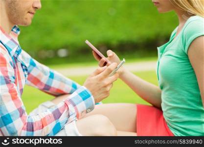 summer, technology, virtual addiction and online communication concept - close up of couple texting with smartphones outdoors