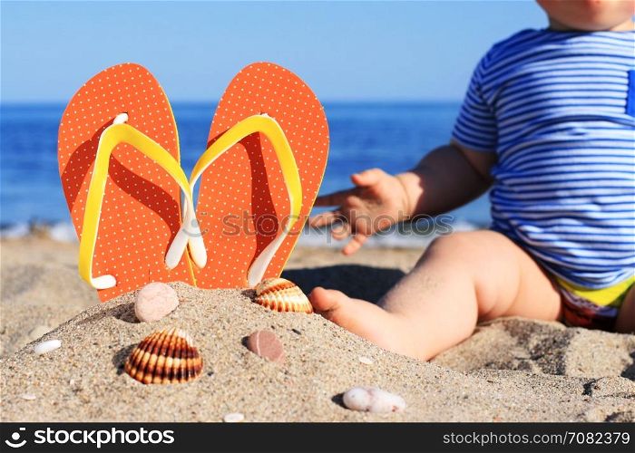 Summer time. Baby and flip-flops on the beach.