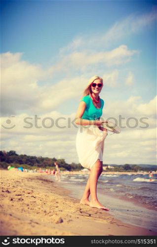 Summer time relax leisure concept. Attractive woman on the beach. Lady wearing sunglasses having fun playing with hat. Attractive woman on the beach.