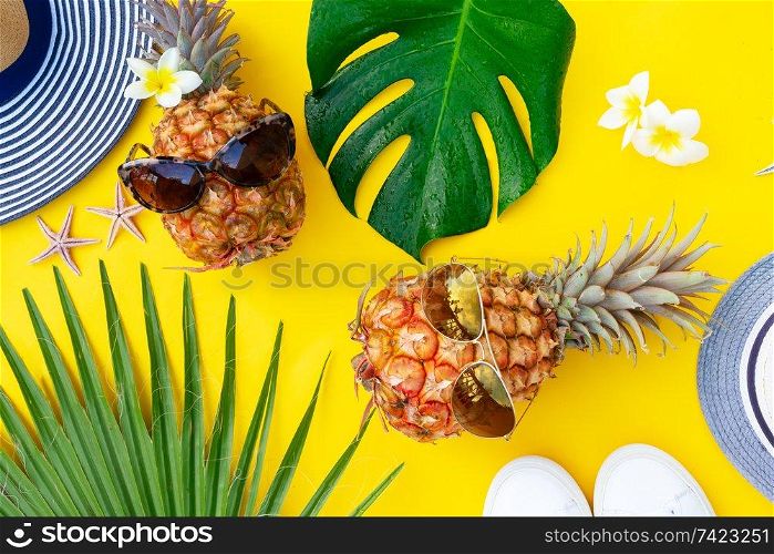 Summer top view flat lay scene with pair pineapples on bright yellow background. Summer flat lay scenery