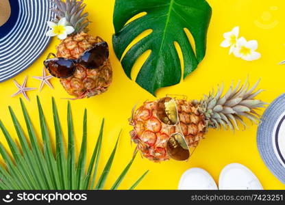 Summer top view flat lay scene with pair pineapples on bright yellow background. Summer flat lay scenery