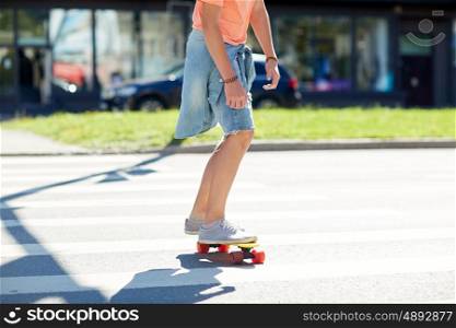 summer, traffic, extreme sport and people concept - teenage boy riding short modern cruiser skateboard on crosswalk in city