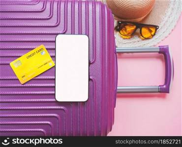 summer travel concept from credit card and suitcase with summer collection on pink background.