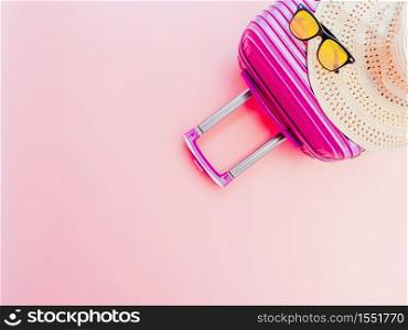 summer travel concept from suitcase with summer accessories on pastel pink background.