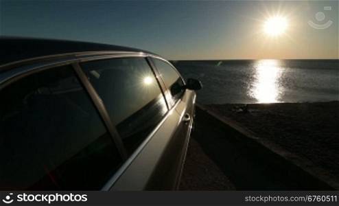 Summer travel destination - car on the beach at sunset, wide-angle lens