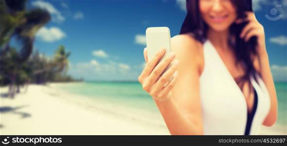 summer, travel, technology and people concept - close up of sexy young woman taking selfie with smartphone over tropical beach with palms background
