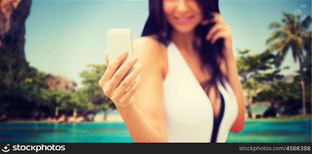 summer, travel, technology and people concept - close up of sexy young woman taking selfie with smartphone over tropical beach with palms background