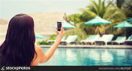 summer, travel, technology and people concept - close up of sexy young woman taking selfie with smartphone over beach and swimming pool background
