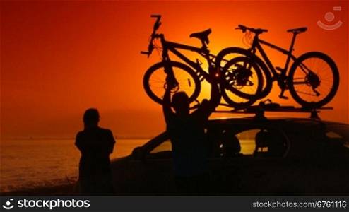 Summer travelers near his car with mounted bikes on beach vacation