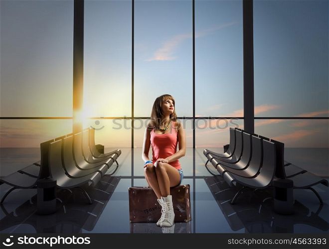 Summer traveling. Young pretty girl traveler at airport sitting on suitcase