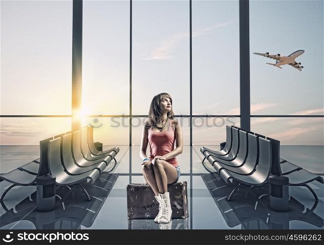 Summer traveling. Young pretty girl traveler at airport sitting on suitcase