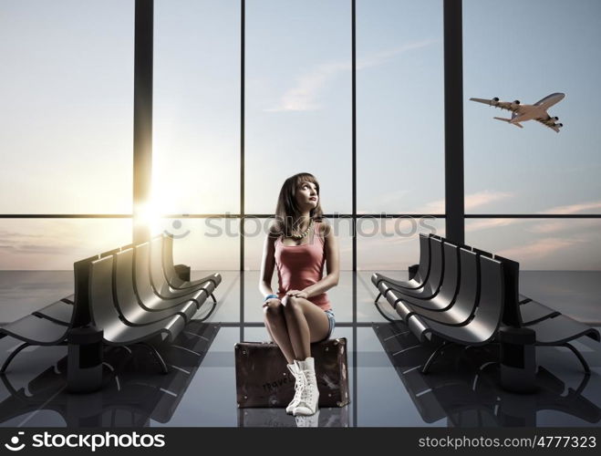 Summer traveling. Young pretty girl traveler at airport sitting on suitcase