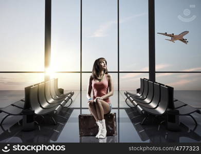 Summer traveling. Young pretty girl traveler at airport sitting on suitcase