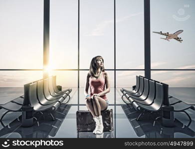 Summer traveling. Young pretty girl traveler at airport sitting on suitcase