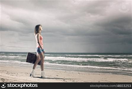 Summer traveling. Young woman tourist walking with suitcase at seaside