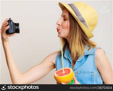 Summer vacation and happy people concept - girl taking self picture selfie with camera while holding citrus fruit in hand
