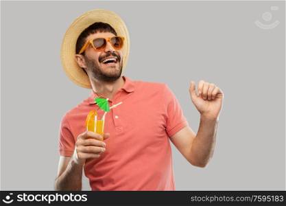 summer, vacation and people concept - happy smiling young man in sunglasses and straw hat with orange juice cocktail dancing over grey background. happy man in straw hat with orange juice cocktail