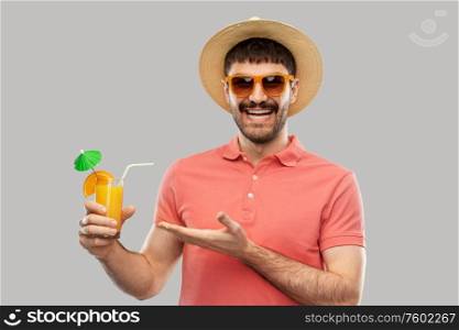 summer, vacation and people concept - happy smiling young man in sunglasses and straw hat with orange juice cocktail over grey background. happy man in straw hat with orange juice cocktail