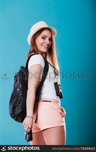 Summer vacation and tourism concept. Young woman in straw hat with backpack camera on blue sideview