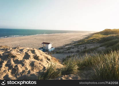 Summer vacation at the beach in the morning light with beach, marram grass, dunes, lifeguard house and sea, on Sylt island, Germany, at the North Sea