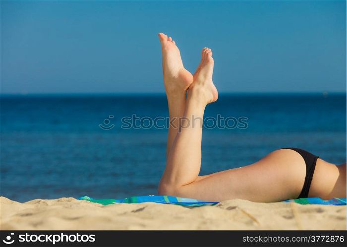 Summer vacation. Closeup of female legs. Sexy girl sunbathing tanning on the beach. Young woman relaxing on the sea coast. Summertime.