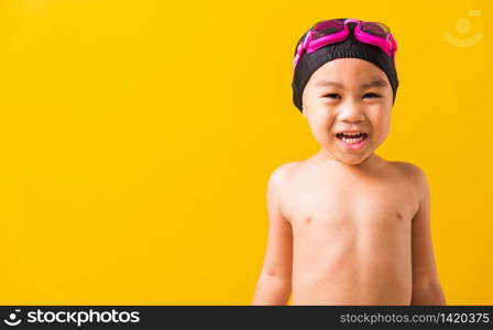 Summer vacation concept, Closeup portrait Asian happy cute little child boy wearing goggles and swimsuit, Kid having fun with in summer vacation looking camera, studio shot isolated yellow background