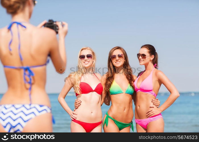 summer vacation, gesture, travel and people concept - group of smiling young women photographing by camera and waving hands on beach