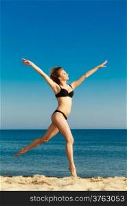 Summer vacation. Girl in bikini running on the beach. Young woman having fun relaxing on the sea coast. Summertime.