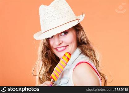 Summer vacation happiness concept. Smiling cheerful woman in straw hat eating popsicle ice cream orange background