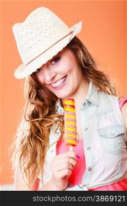 Summer vacation happiness concept. Smiling cheerful woman in straw hat eating popsicle ice cream orange background