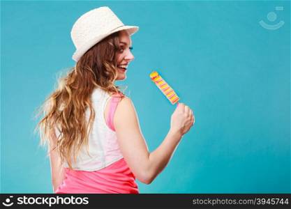 Summer vacation happiness concept. Smiling joyful and cheerful woman fashionable female model eating popsicle ice pop on blue background