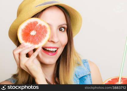 Summer vacation. Happy funny girl tourist in hat holding grapefruit citrus fruit on gray.