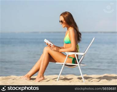 summer vacation, holidays and people concept - smiling young woman sunbathing in lounge on beach