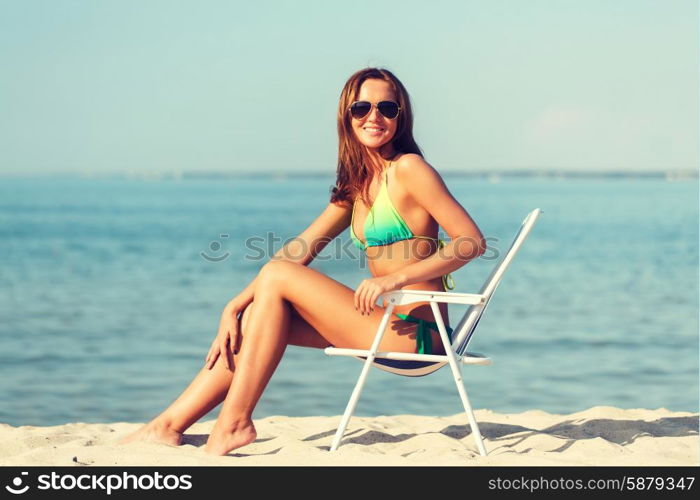 summer vacation, holidays and people concept - smiling young woman sunbathing in lounge on beach