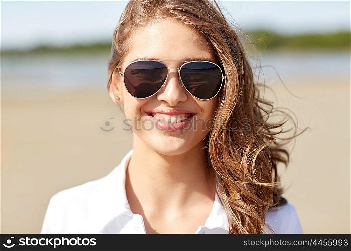 summer vacation, holidays, eyewear and people concept - smiling young woman in sunglasses on beach