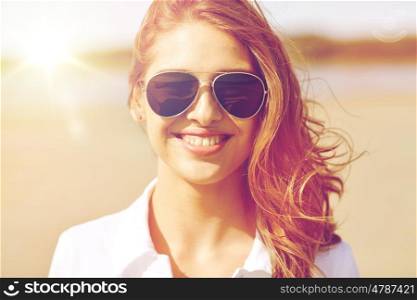 summer vacation, holidays, eyewear and people concept - smiling young woman in sunglasses on beach