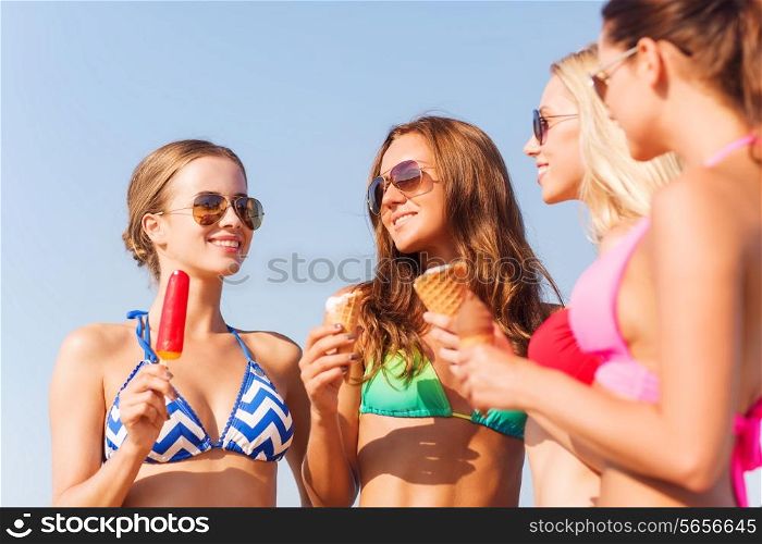 summer vacation, holidays, food, travel and people concept - group of smiling young women eating ice cream on beach