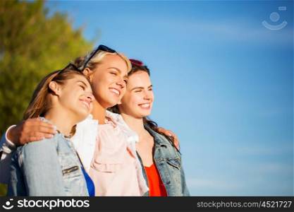 summer vacation, holidays, friendship and people concept - group of happy smiling young women or teenage girls hugging outdoors