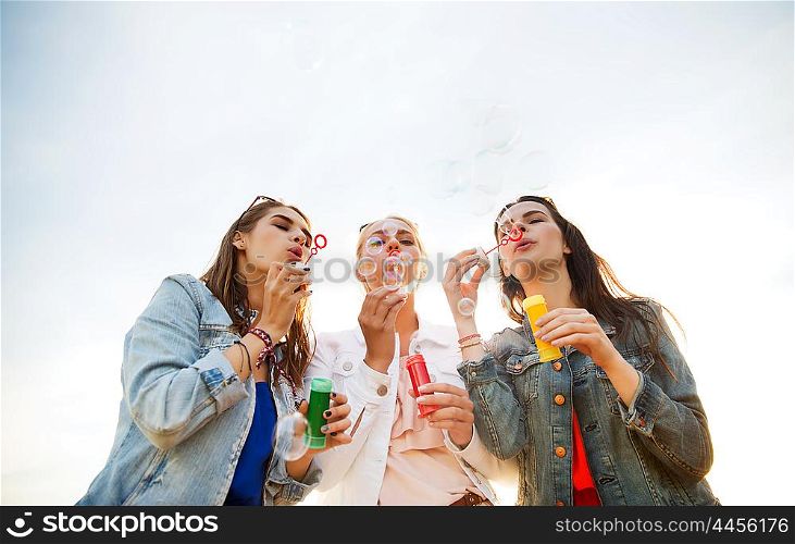 summer vacation, holidays, fun and people concept - group of happy young women or teenage girls blowing bubbles outdoors