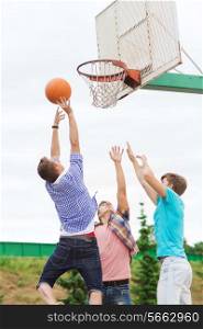 summer vacation, holidays, games and friendship concept - group of teenagers playing basketball outdoors