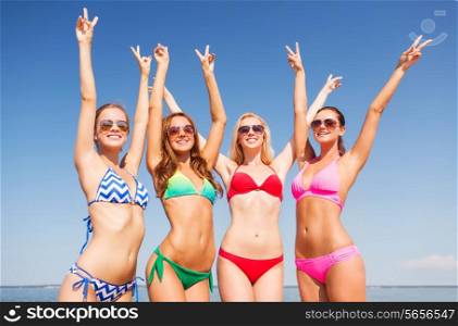 summer vacation, holidays, gesture, travel and people concept - group of smiling young women showing peace or victory sign on beach