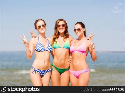 summer vacation, holidays, gesture, travel and people concept- group of smiling young women showing peace or victory sign on beach