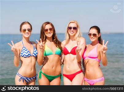 summer vacation, holidays, gesture, travel and people concept- group of smiling young women showing peace or victory sign on beach