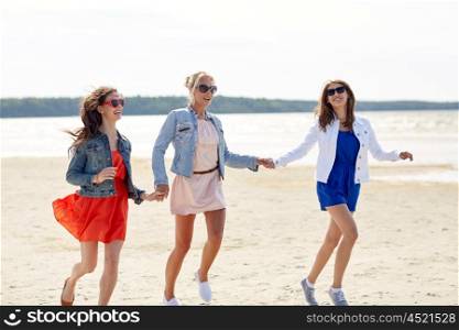 summer vacation, holidays, travel and people concept - group of smiling young women in sunglasses and casual clothes running along beach