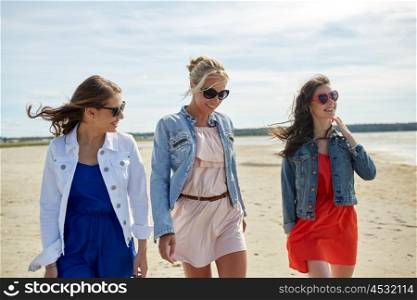 summer vacation, holidays, travel and people concept - group of smiling young women in sunglasses and casual clothes walking along beach