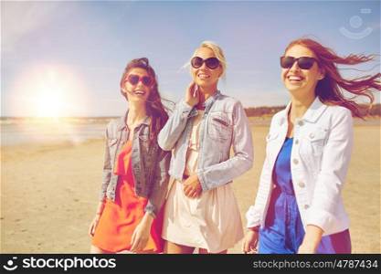 summer vacation, holidays, travel and people concept - group of smiling young women in sunglasses and casual clothes walking along beach