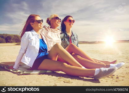summer vacation, holidays, travel and people concept - group of smiling young women in sunglasses and casual clothes on sunbathing on beach blanket