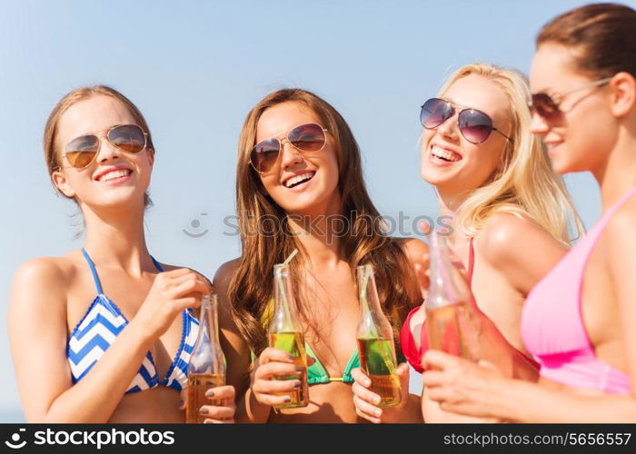 summer vacation, holidays, travel and people concept - group of smiling young women sunbathing and drinking on beach